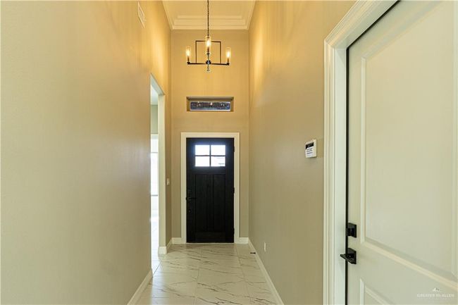 Doorway featuring marble finish floor, crown molding, baseboards, and an inviting chandelier | Image 33