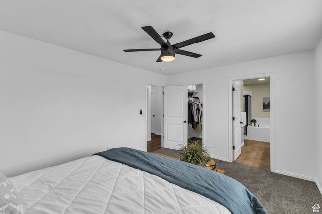 Carpeted bedroom featuring a ceiling fan, ensuite bathroom, a closet, a spacious closet, and baseboards | Image 15
