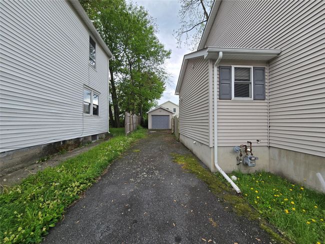 View of side of home with asphalt driveway, a detached garage, and an outdoor structure | Image 12