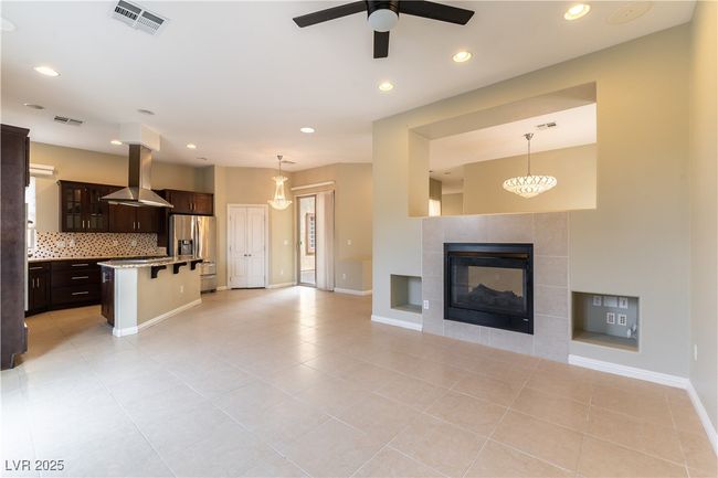 Unfurnished living room featuring baseboards, ceiling fan, visible vents, and a tiled fireplace | Image 10