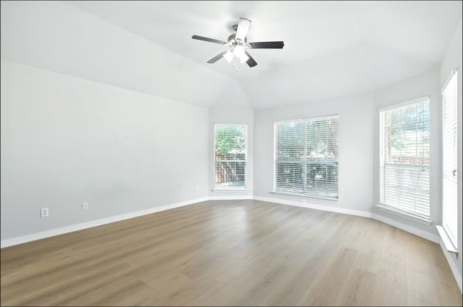 Empty room featuring ceiling fan, wood finished floors, and vaulted ceiling | Image 26