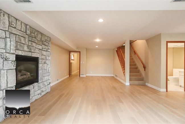 Unfurnished living room featuring wood finished floors, stairs, recessed lighting, and a stone fireplace | Image 33