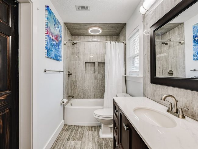 Bathroom with shower / bath combination with curtain, toilet, wood finished floors, visible vents, and vanity | Image 12