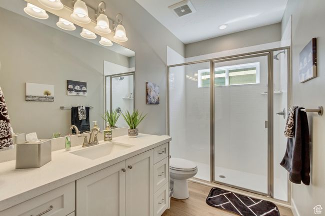Bathroom featuring a shower stall, wood finished floors, visible vents, toilet, and vanity | Image 24