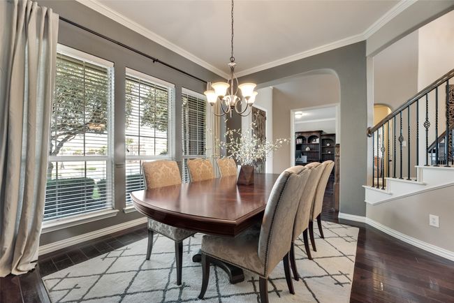 Dining space with a chandelier, crown molding, hardwood / wood-style flooring, stairs, and arched walkways | Image 13