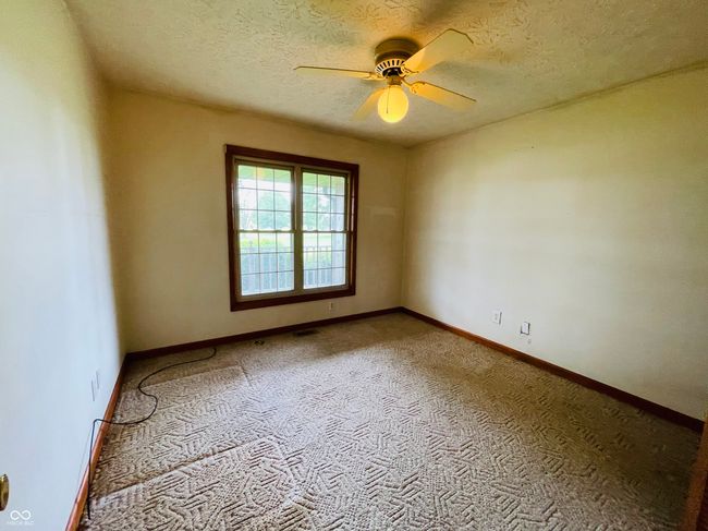 carpeted empty room with a ceiling fan, baseboards, and a textured ceiling | Image 15