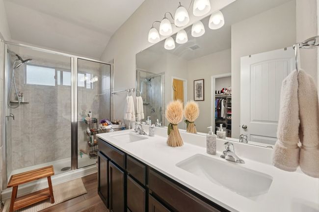 Full bathroom with a stall shower, double vanity, a walk in closet, and lofted ceiling | Image 28