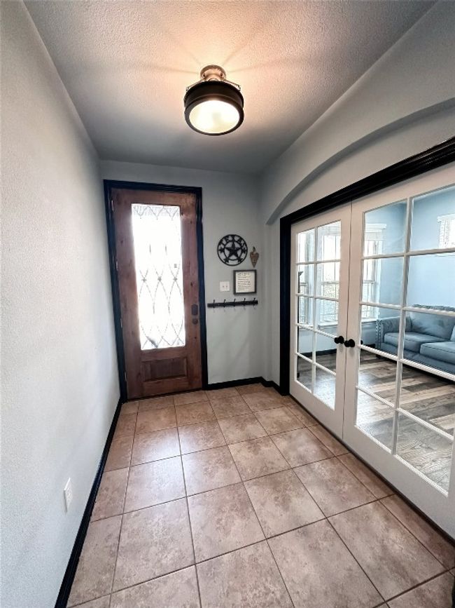 Entryway with french doors to front room, a textured ceiling, and light tile patterned flooring | Image 5