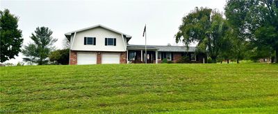 home featuring a garage and a front lawn | Image 1