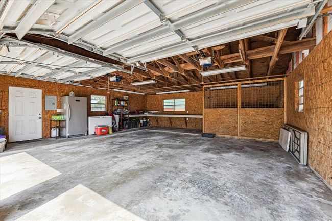 Two car detached garage just off the home has a work bench area, door access to the covered back patio for easy entry into the home, along with a pet kennel that leads to a fenced pet run behind the garage | Image 37