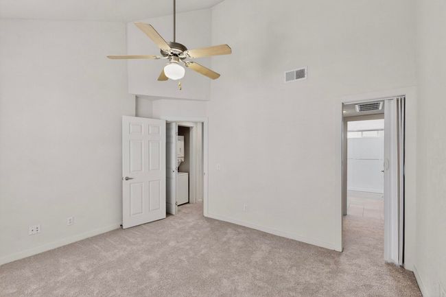 Unfurnished bedroom with a high ceiling, light carpet, and estacked washer and dryer | Image 25