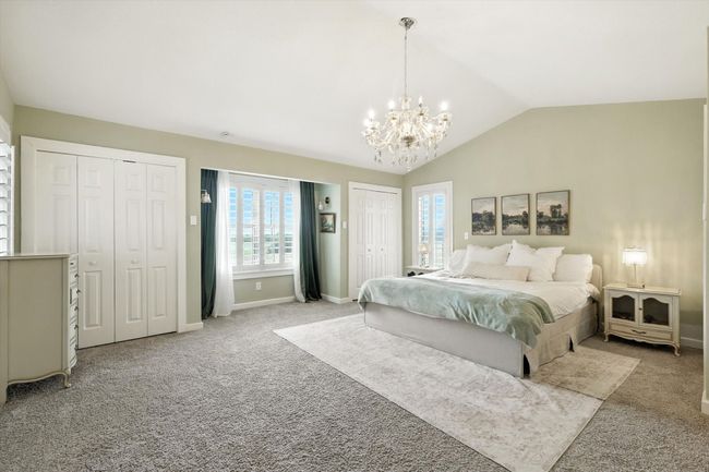 Bedroom with multiple closets, light colored carpet, lofted ceiling, and a chandelier | Image 22