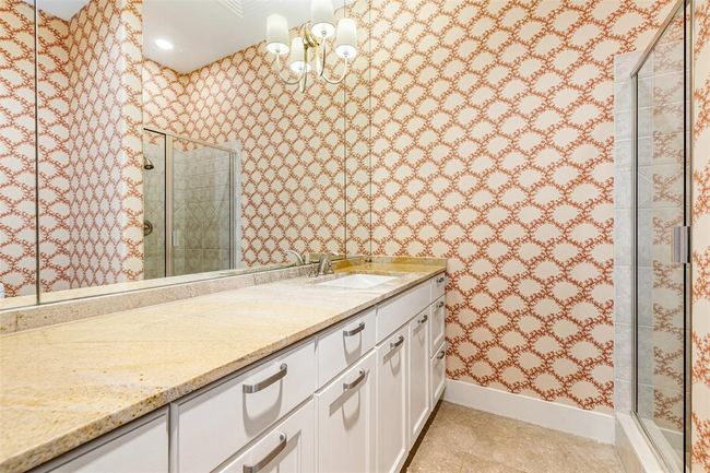 En suite bath with limestone floors, marble countertops, extra cabinetry and glass framed shower. | Image 18