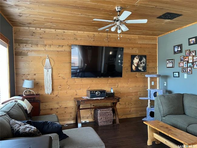 Living area with wood finished floors, a ceiling fan, wooden walls, and wood ceiling | Image 20
