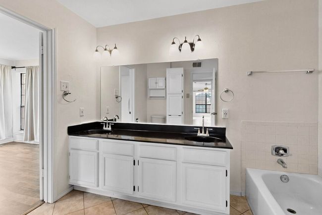 Bathroom with double vanity, a garden tub, tile patterned flooring, toilet, and a ceiling fan | Image 23