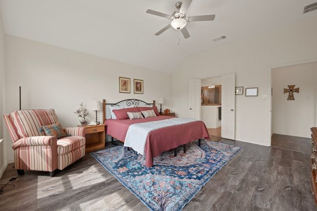 Bedroom featuring wood finished floors, vaulted ceiling, baseboards, and ceiling fan | Image 13