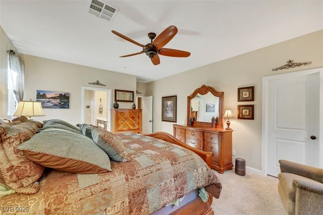 Carpeted bedroom featuring connected bathroom, baseboards, visible vents, and ceiling fan | Image 24