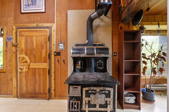Detailed view of a wood stove, wood finished floors, and wooden walls | Image 18