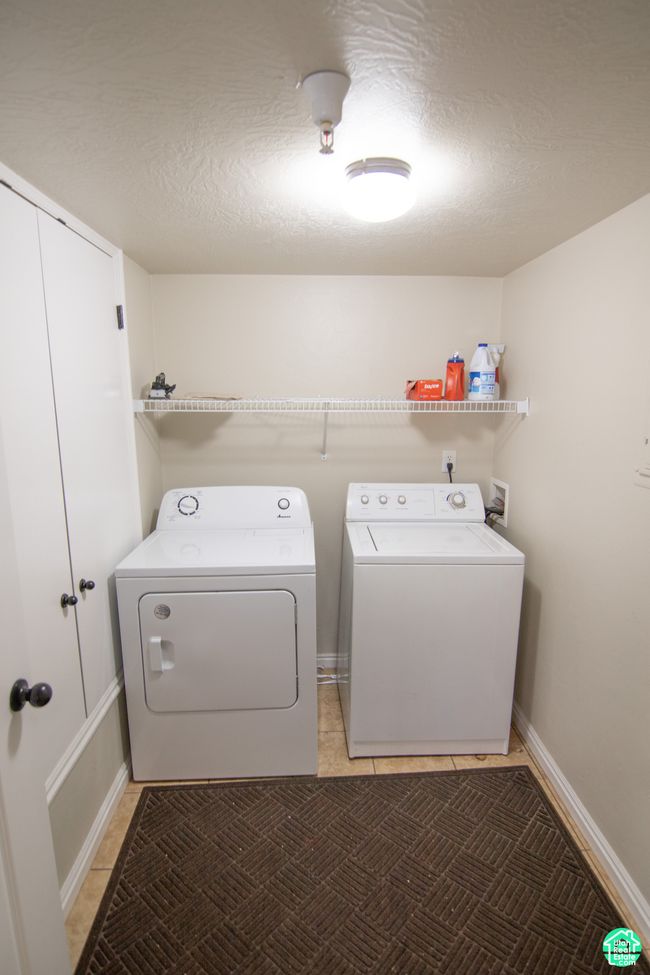 Laundry area with washing machine and clothes dryer, light tile patterned floors, and a textured ceiling | Image 11