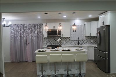 Kitchen with hanging light fixtures, stainless steel appliances, and white cabinetry | Image 3