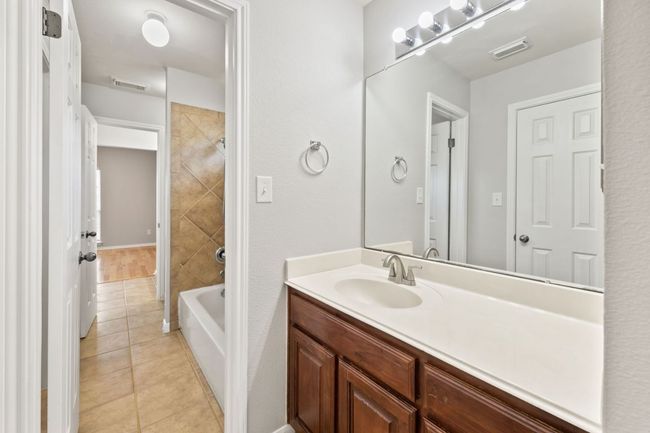 Full bathroom with vanity, tile patterned flooring, and shower / bathtub combination | Image 28