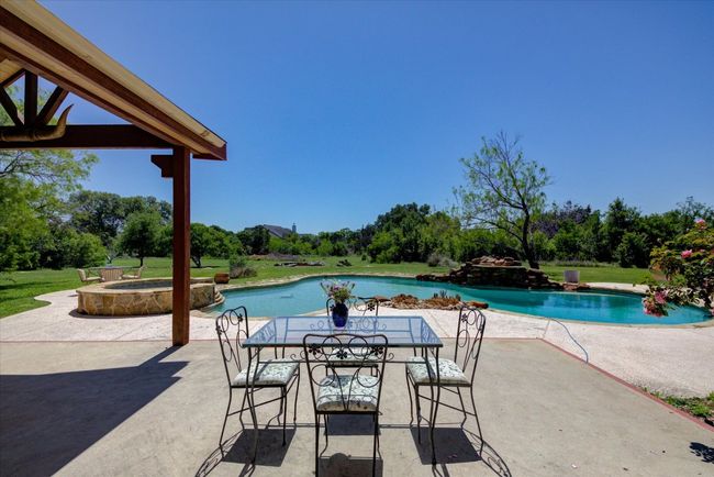 View of the swimming pool featuring outdoor dining space, a patio, and a pool with diving board and spa. Enjoy the nature around you! | Image 32