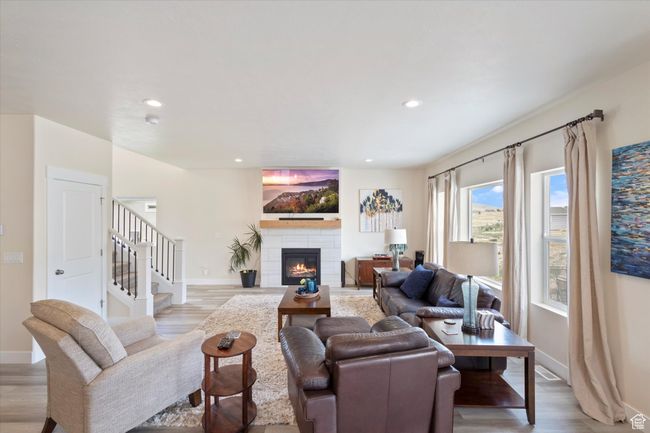 Living room with light wood-style floors, a tiled fireplace, recessed lighting, and stairway | Image 11