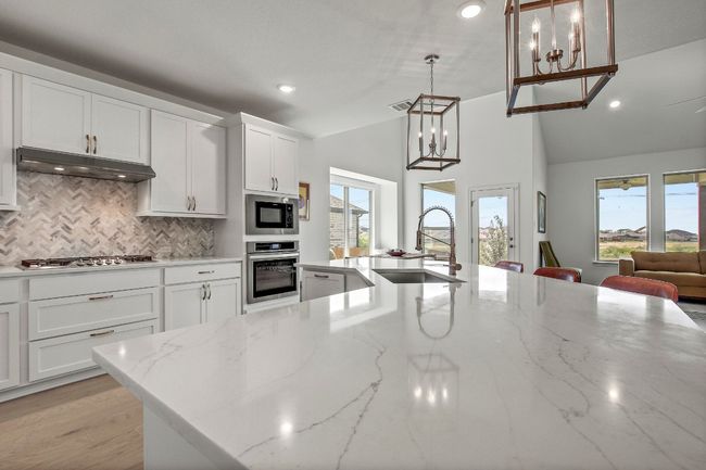 Kitchen with stainless steel appliances, under cabinet range hood, backsplash, recessed lighting, and freshly painted white cabinetry - check out this island kitchen and modern lighting ! | Image 9