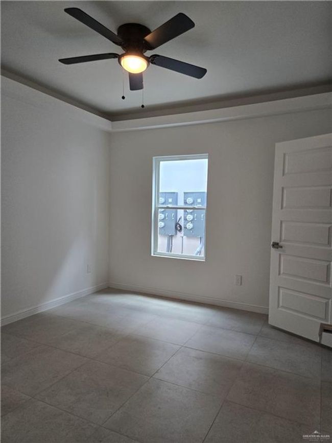 Empty room with a ceiling fan and tile patterned flooring | Image 11