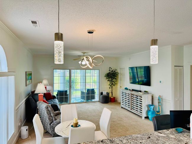 Dining room featuring a textured ceiling, carpet flooring, crown molding, and a chandelier | Image 23