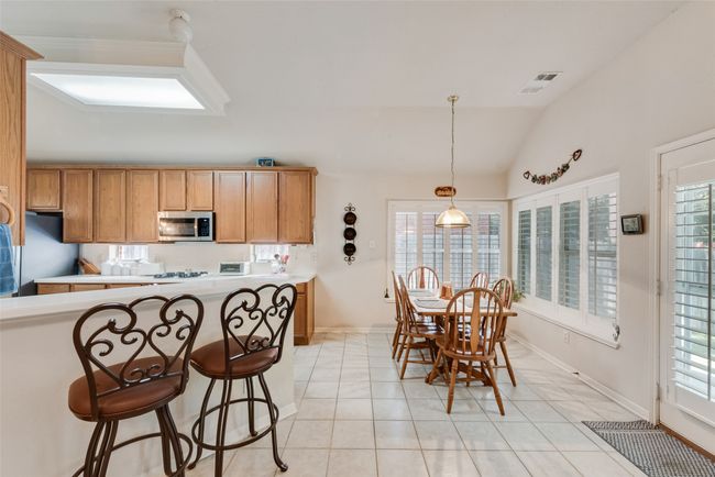 Kitchen with appliances with stainless steel finishes, vaulted ceiling, light tile patterned floors, baseboards, and plenty of natural light | Image 12