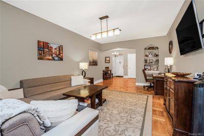 Living room with a notable chandelier, light parquet floors, and built in shelves | Image 2