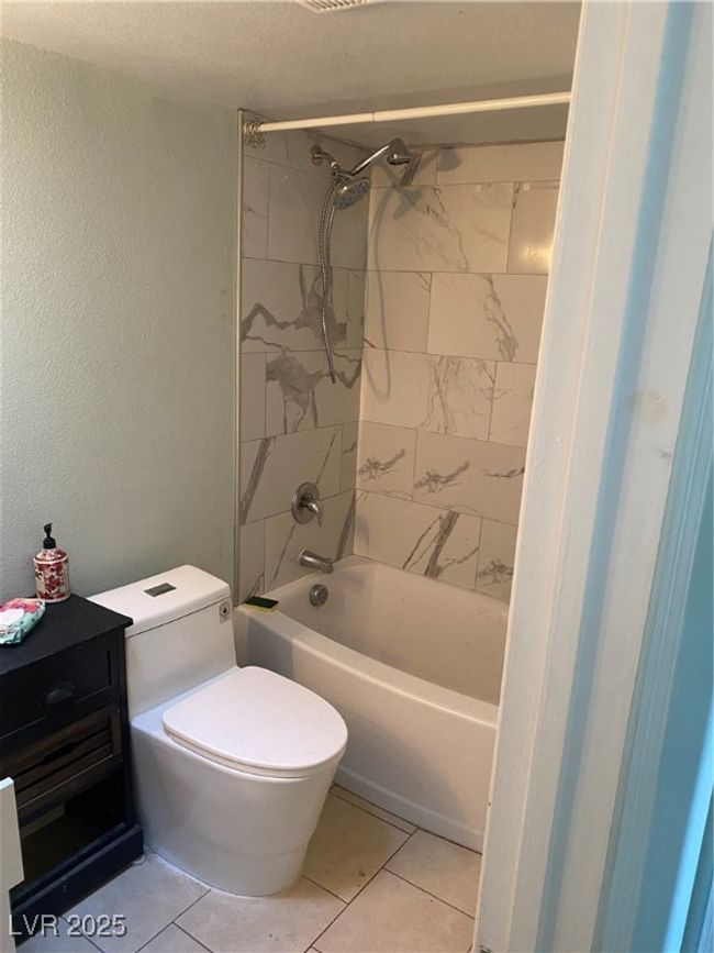 Bathroom with toilet, a textured wall, and shower / bathing tub combination | Image 14