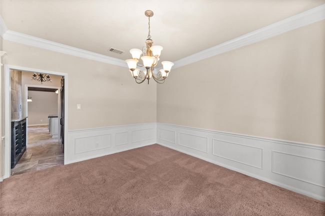 Carpeted spare room with ornamental molding, a chandelier, wainscoting, and a decorative wall | Image 6