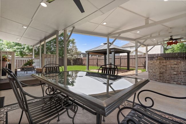 View of patio / terrace with ceiling fan, a fenced backyard, a gazebo, and outdoor dining area | Image 40