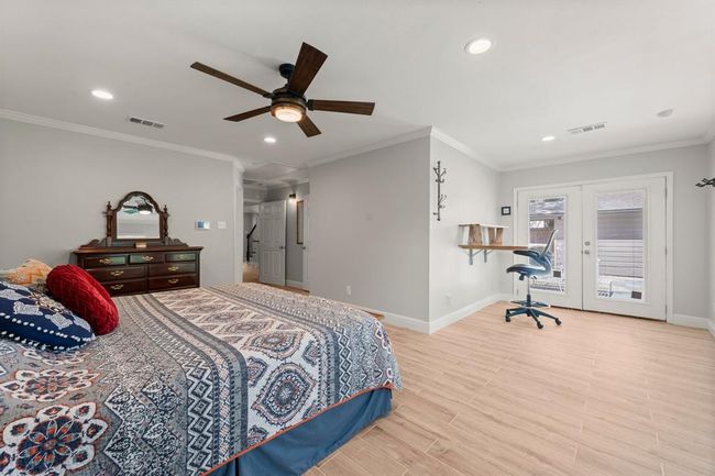 Spacious bedroom features ample natural light from large French doors, and a cozy nook for a desk or seating area. | Image 21