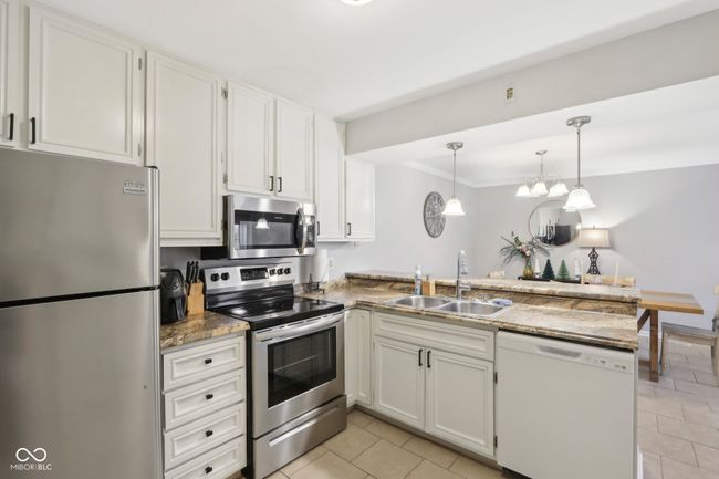 kitchen with a peninsula, a sink, white cabinetry, appliances with stainless steel finishes, and light tile patterned floors | Image 13