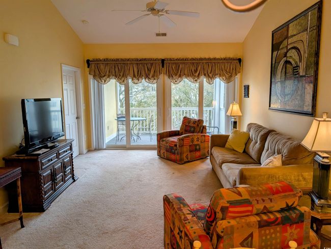 Carpeted living room featuring a ceiling fan, high vaulted ceiling, and visible vents | Image 4