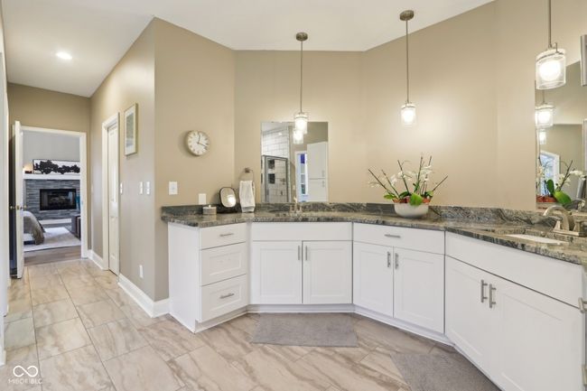 ensuite bathroom with double vanity, a sink, a glass covered fireplace, and a tile shower | Image 28