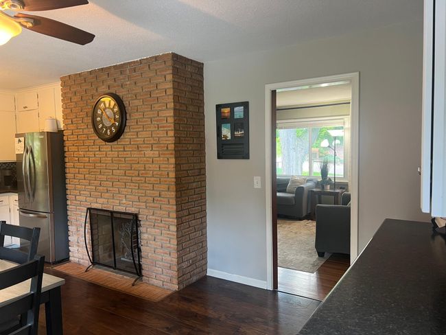 View of the fireplace from the back door, looking into the living room, kitchen and dining room. | Image 9