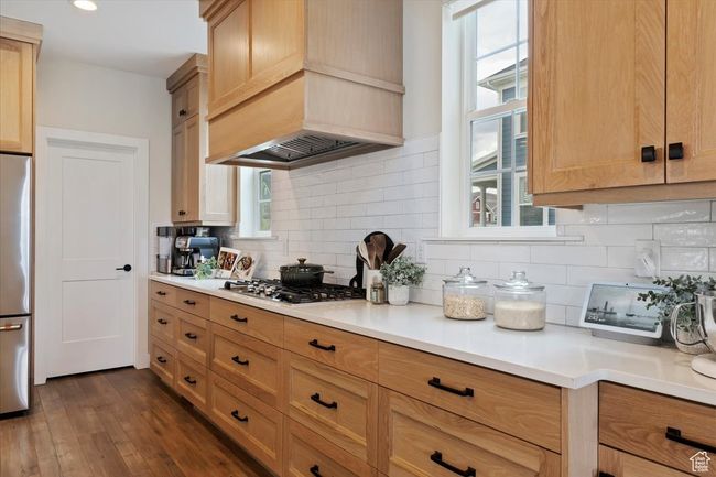 Kitchen featuring light countertops, custom exhaust hood, appliances with stainless steel finishes, and dark wood-style flooring | Image 13
