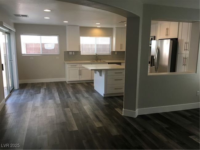 Kitchen featuring refrigerator, a sink, white cabinets, and dark wood finished floors | Image 5