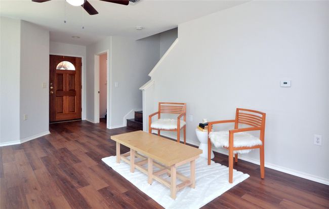 Living area with ceiling fan, wood finished floors, baseboards, and stairway | Image 8