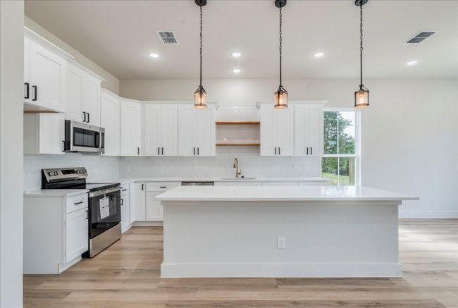Kitchen featuring appliances with stainless steel finishes, a center island, tasteful backsplash, open shelves, and light countertops | Image 8