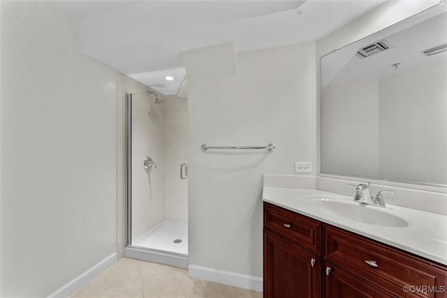 Full bathroom with vanity, tile patterned flooring, baseboards, and a stall shower | Image 20