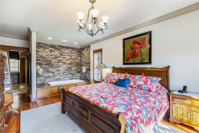 Bedroom featuring an inviting chandelier, ornamental molding, and whirlpool spa tub stone veneer wall surround | Image 26