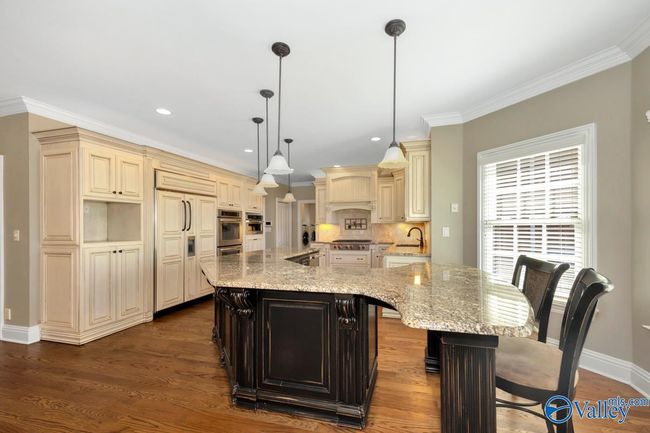 Wood flooring, wood cabinetry, kitchen island with bar seating, recessed lighting | Image 18