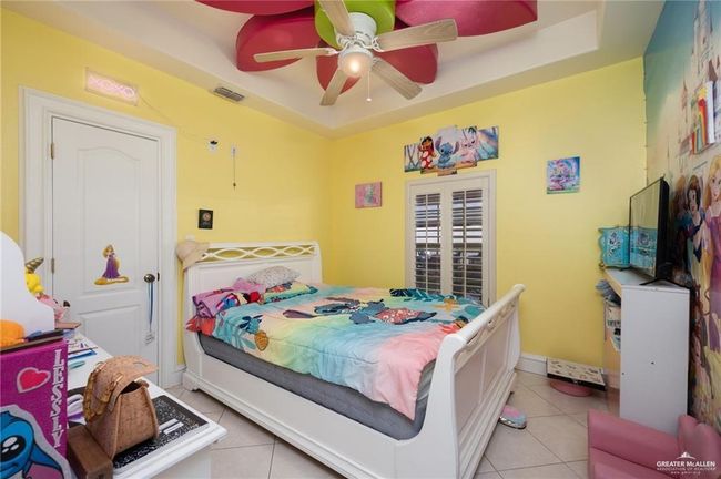 Bedroom featuring a raised ceiling, ceiling fan, and light tile patterned flooring | Image 7