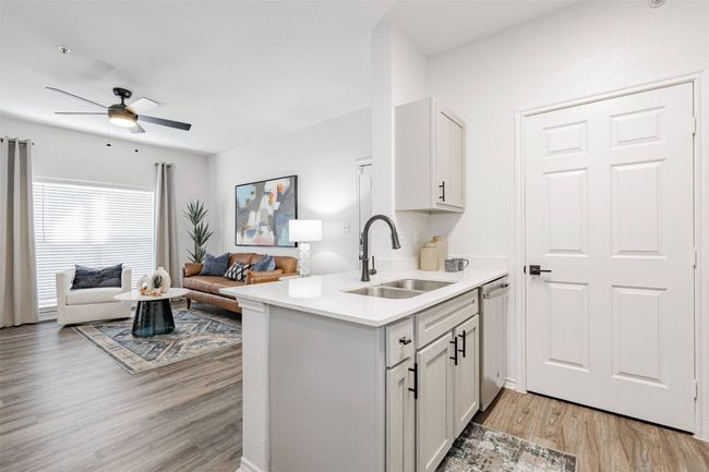 Kitchen featuring kitchen peninsula, light wood-type flooring, sink, dishwasher, and white cabinetry | Image 7