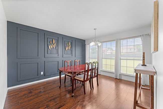 Dining area with a chandelier, dark wood-style flooring, and a decorative wall | Image 14